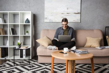 homem sentado no sofá estudando com um notebook no colo